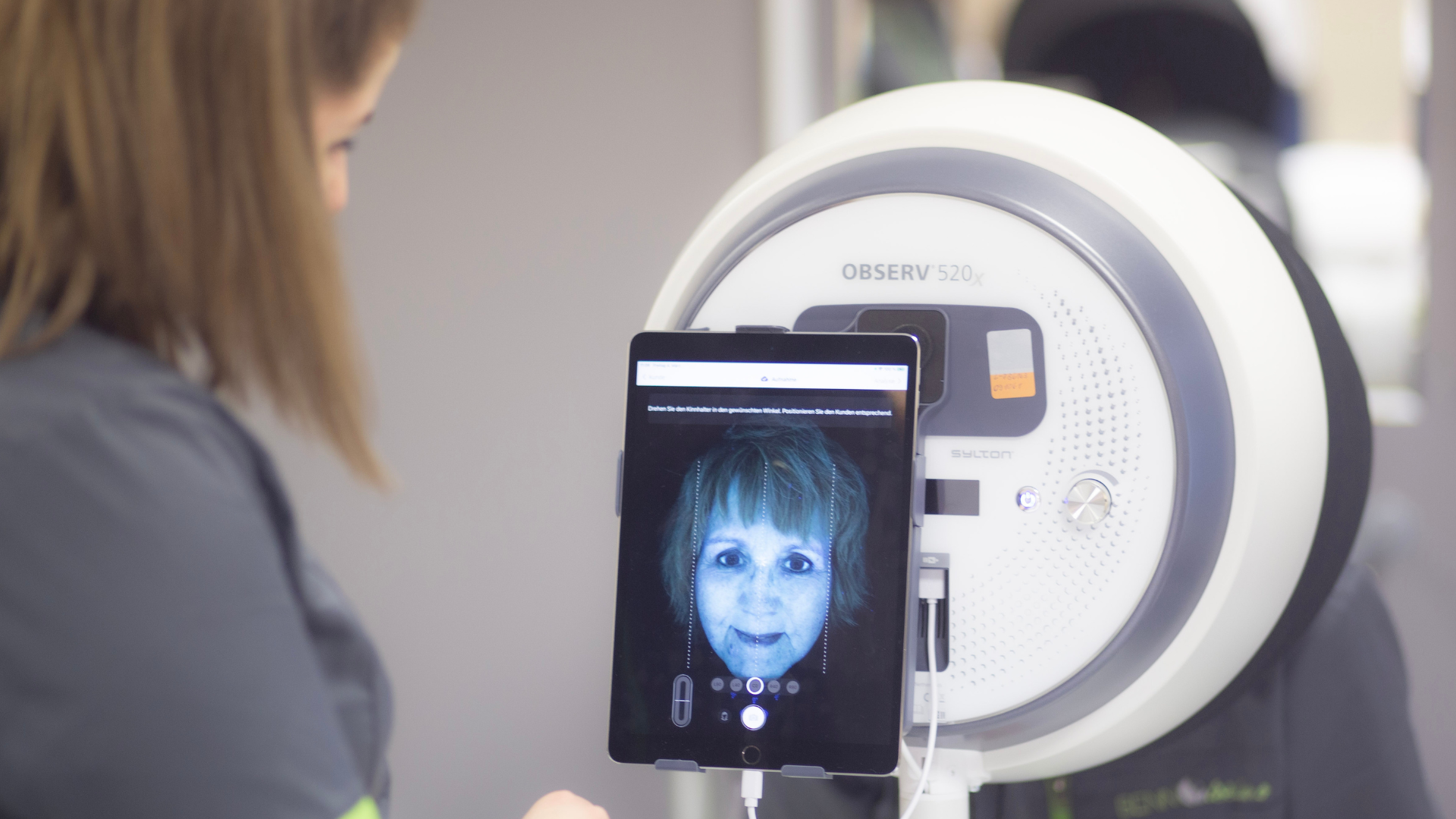 Kosmetikerin schaut sich die Hautanalysefotos vom Observe an