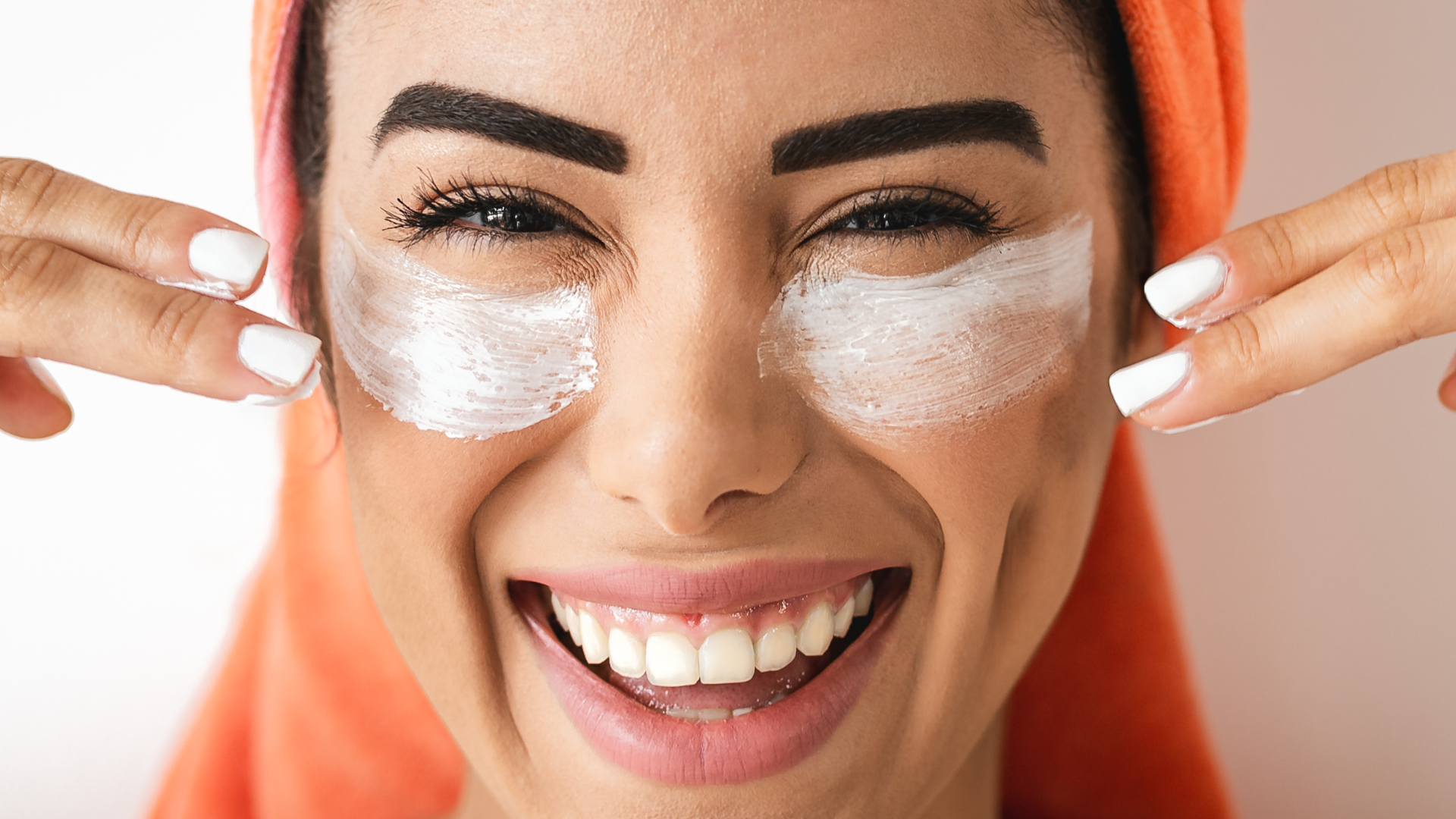 47 Eine Frau trägt sich ihre Augenpflege auf und lacht